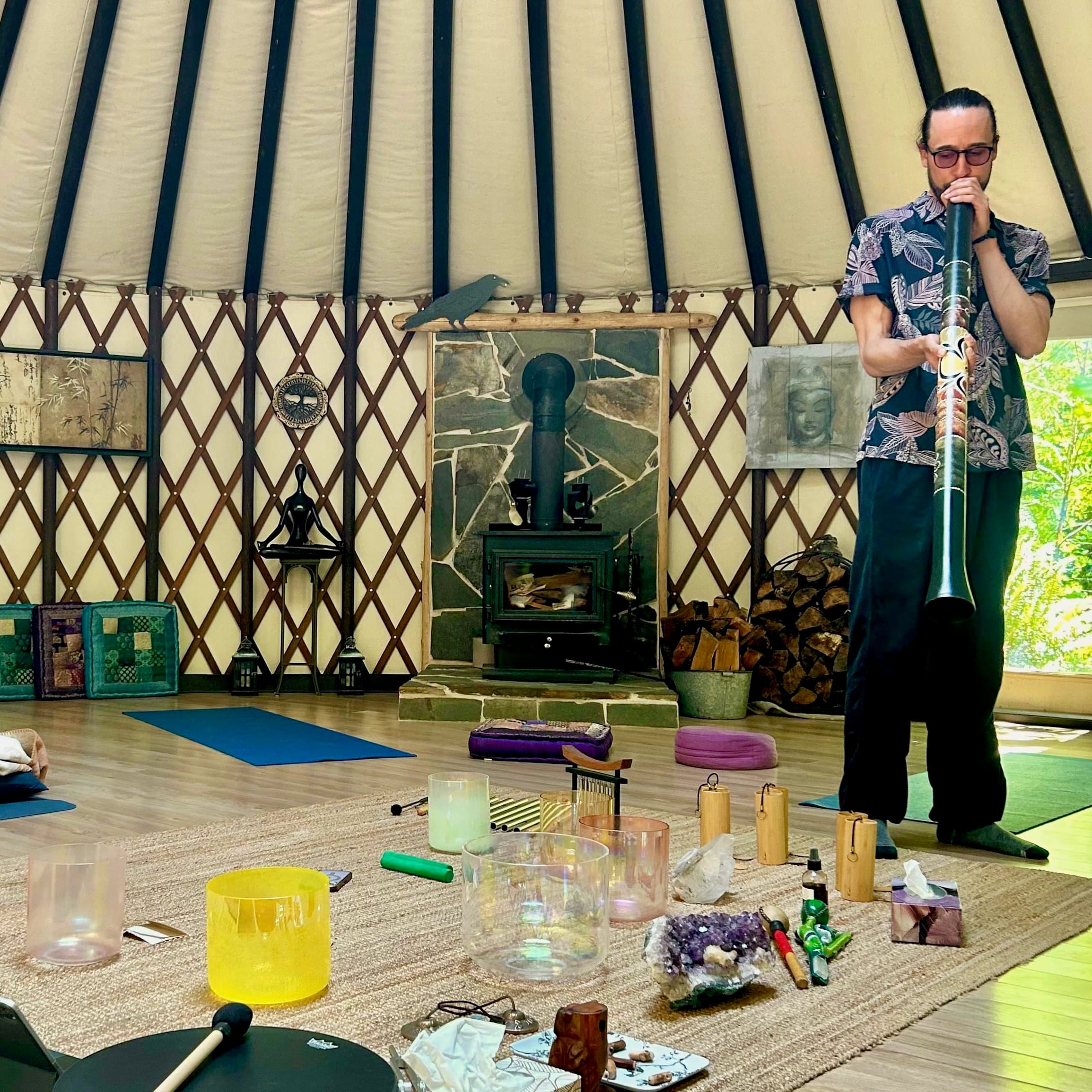 A facilitator playing a didgeridoo inside the yurt during an Inward sound bath.